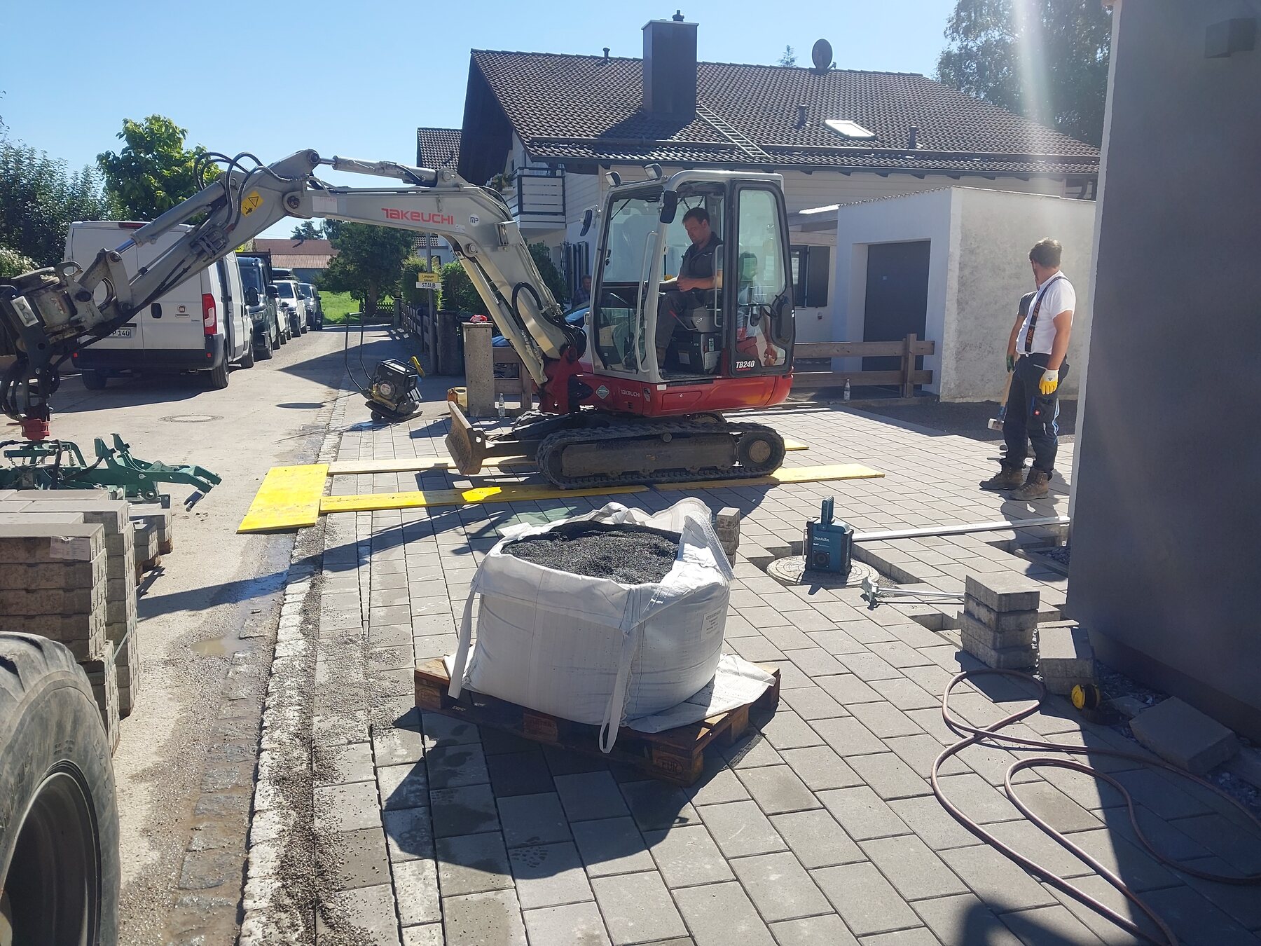 Kompaktbagger der Hitzler GmbH bei Pflasterarbeiten auf einem beengten Grundstück